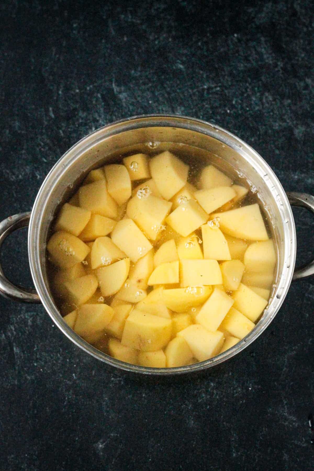 Diced potatoes in a pot of cold water.