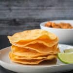 Stack of baked tostada shells with wavy edges.