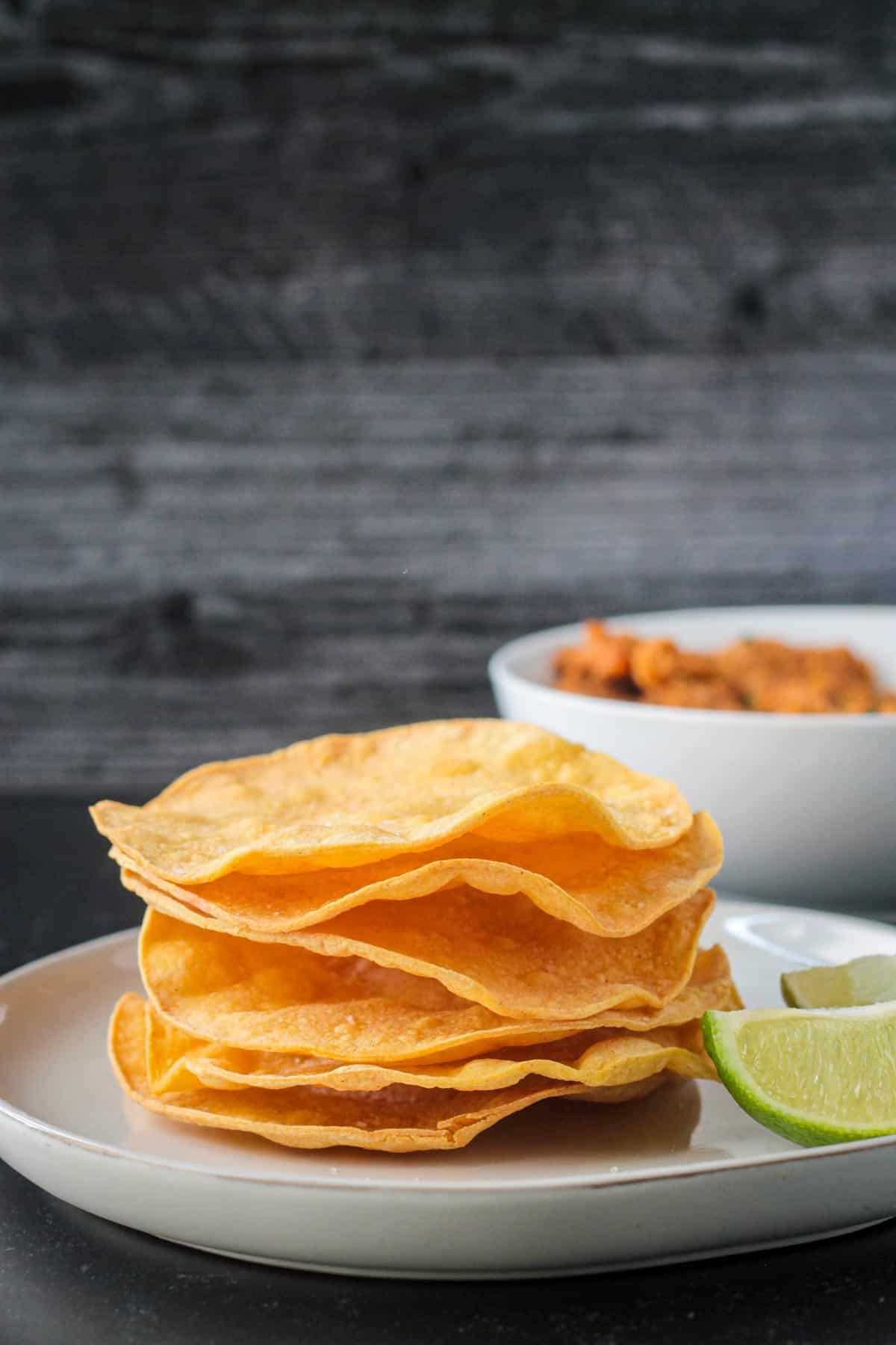 Stack of baked tostada shells with wavy edges.