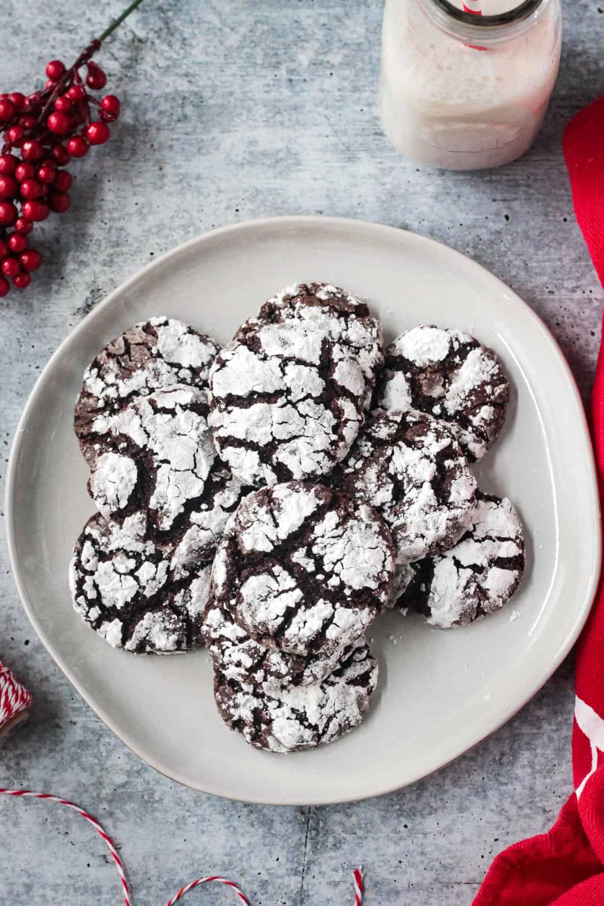 Pile of chocolate crinkle cookies dusted with powdered sugar on a plate.