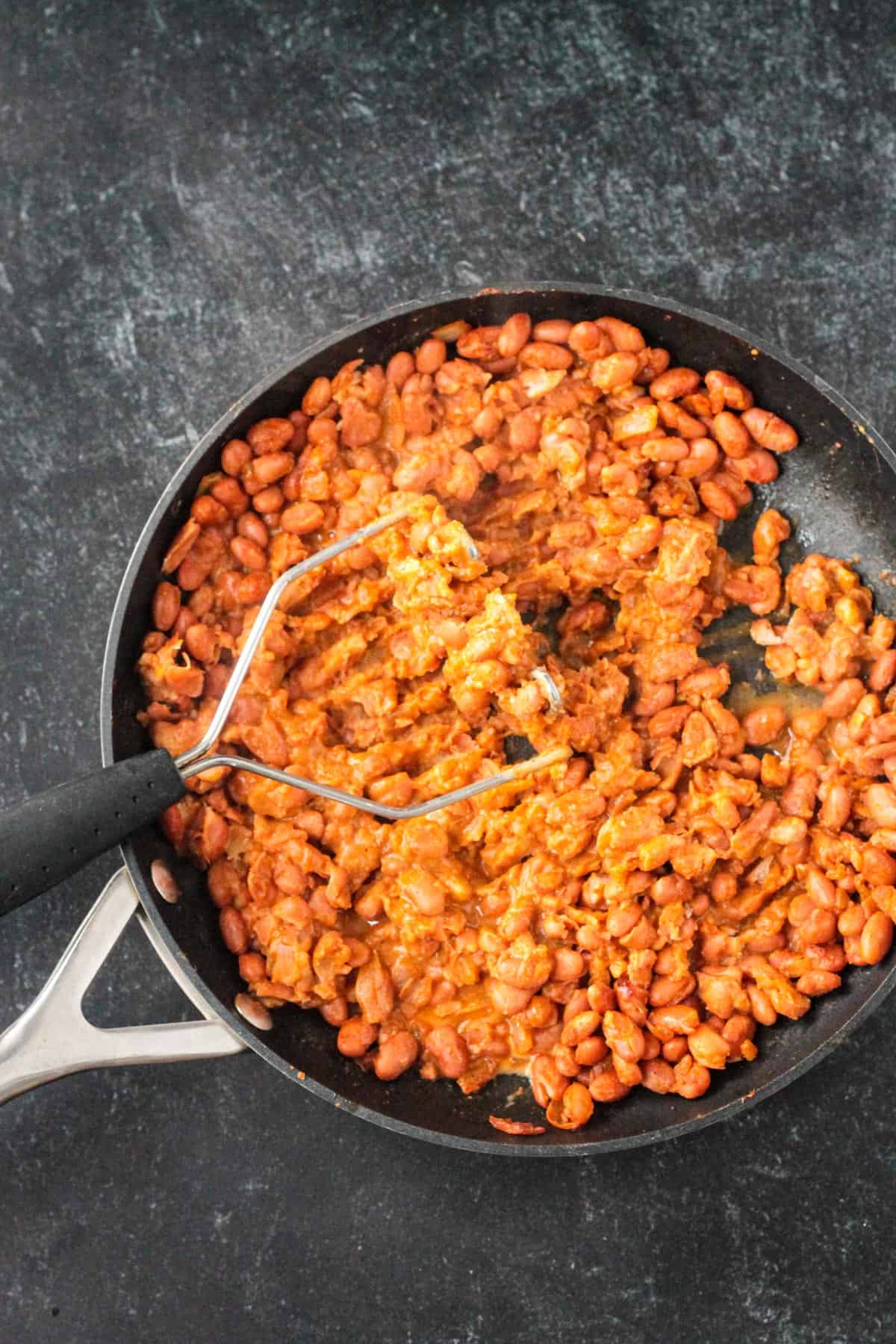 Mashing the pinto beans with a potato masher.