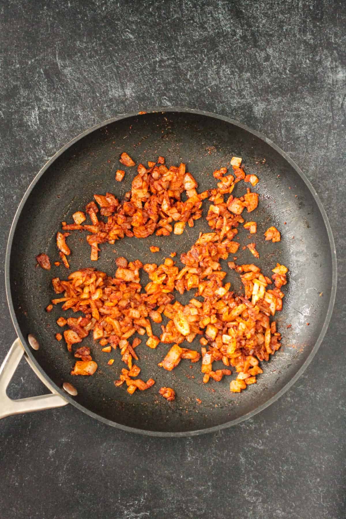 Onions sautéed with spices in a skillet.