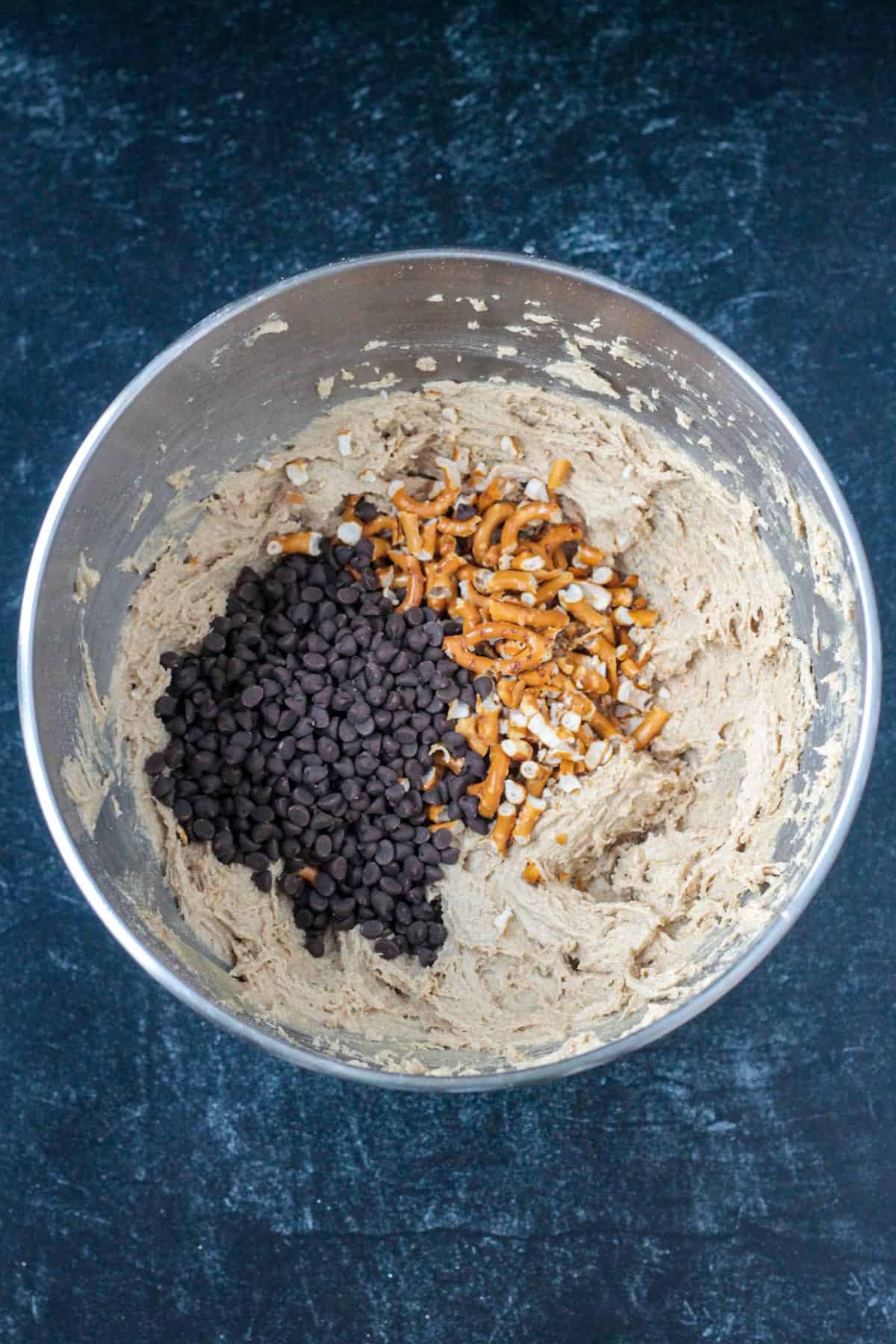 Adding chocolate chips and pretzels to the dough.