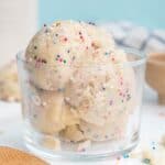 Scoops of edible dough with sprinkles in a glass.