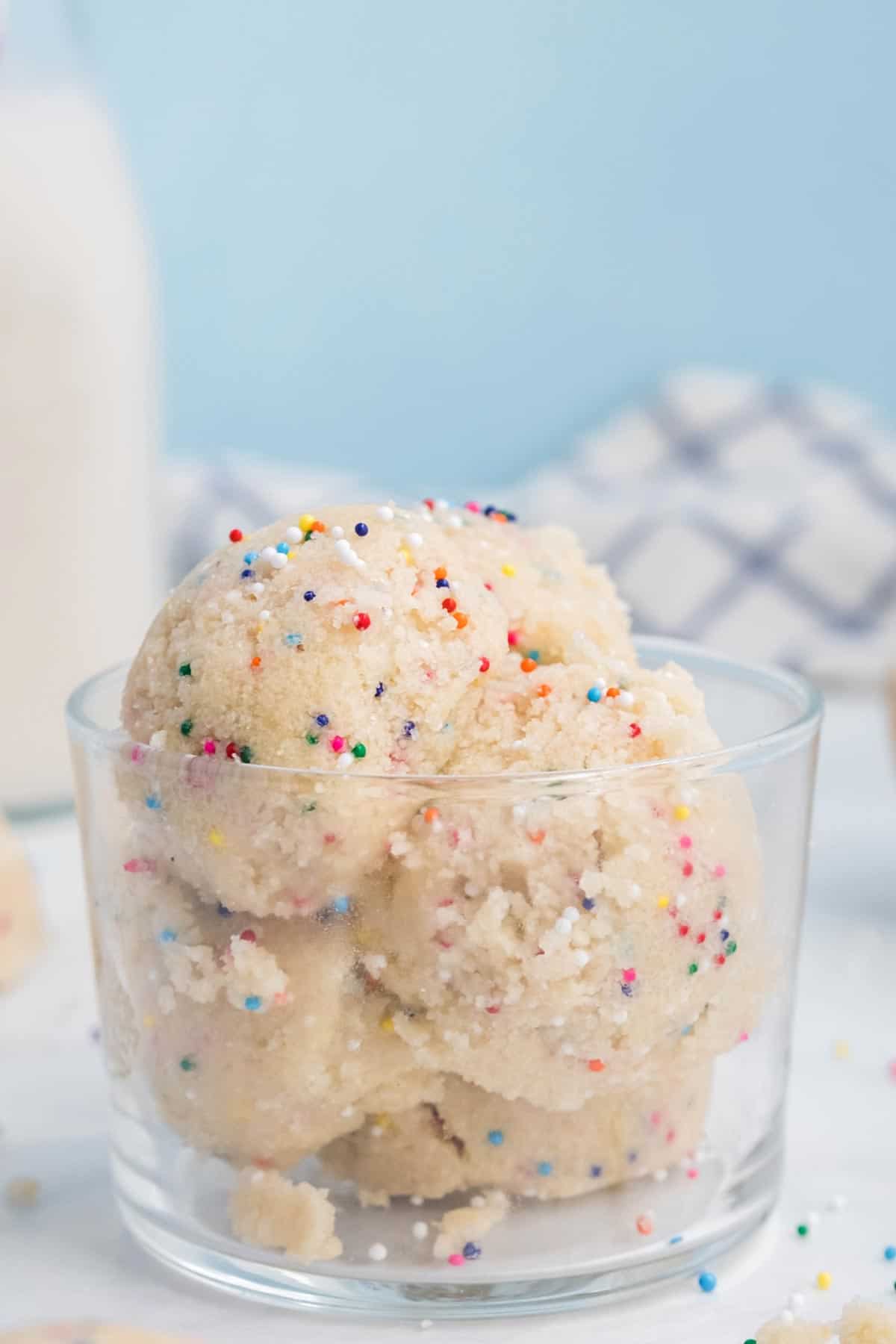 Scoops of edible dough with sprinkles in a glass.