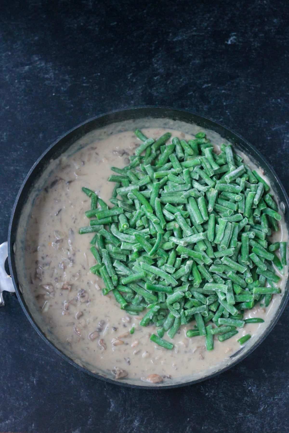 Adding frozen cut green beans to the mushroom sauce.