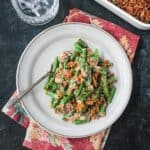 Serving of vegan green bean casserole on a plate with a fork.