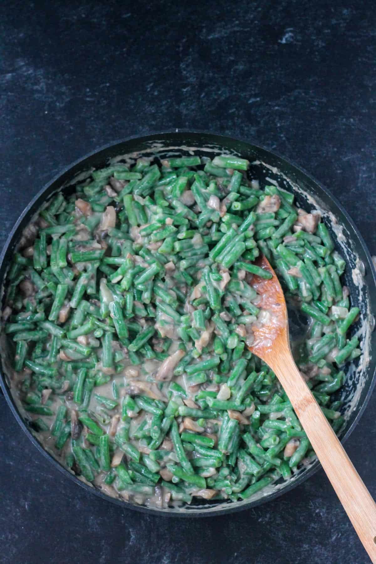 Mixing the green beans into the mushroom sauce.