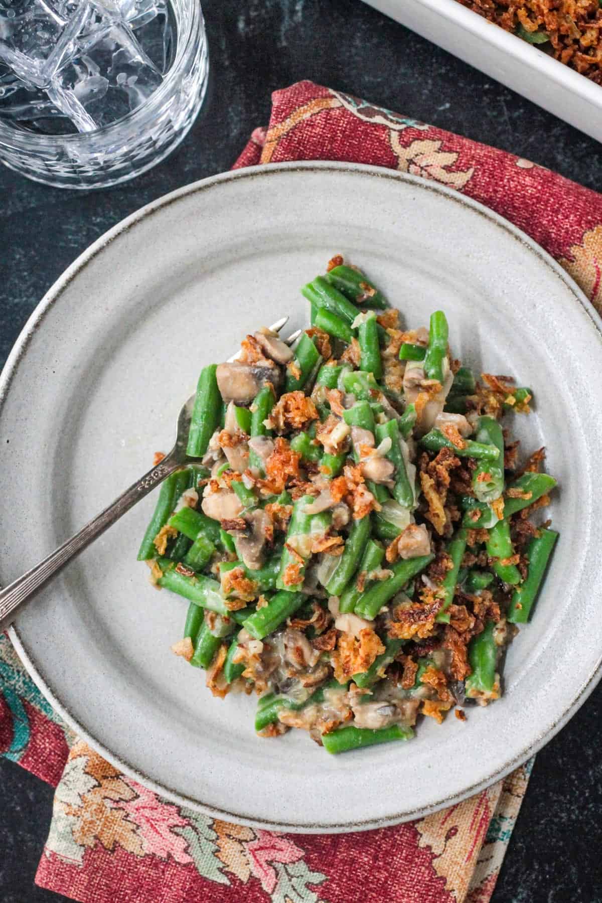 Serving of vegan green bean casserole on a plate with a fork.