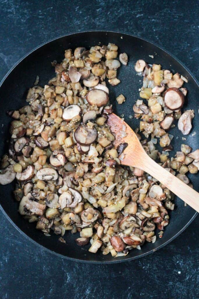 Sautéed eggplant and mushrooms in a skillet.