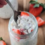Spoonful of overnight oats with coconut milk being lifted from a jar.