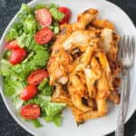 Serving of vegan pasta bake on a plate with salad greens.