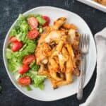 Serving of vegan pasta bake on a plate with salad greens.