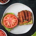 Tempeh bacon on an open face sandwich.