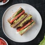 Two halves of a vegan blt sandwich on a plate.