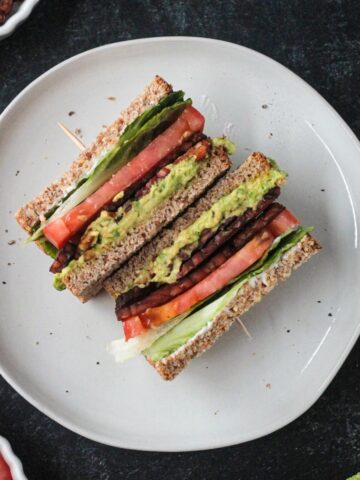 Two halves of a vegan blt sandwich on a plate.