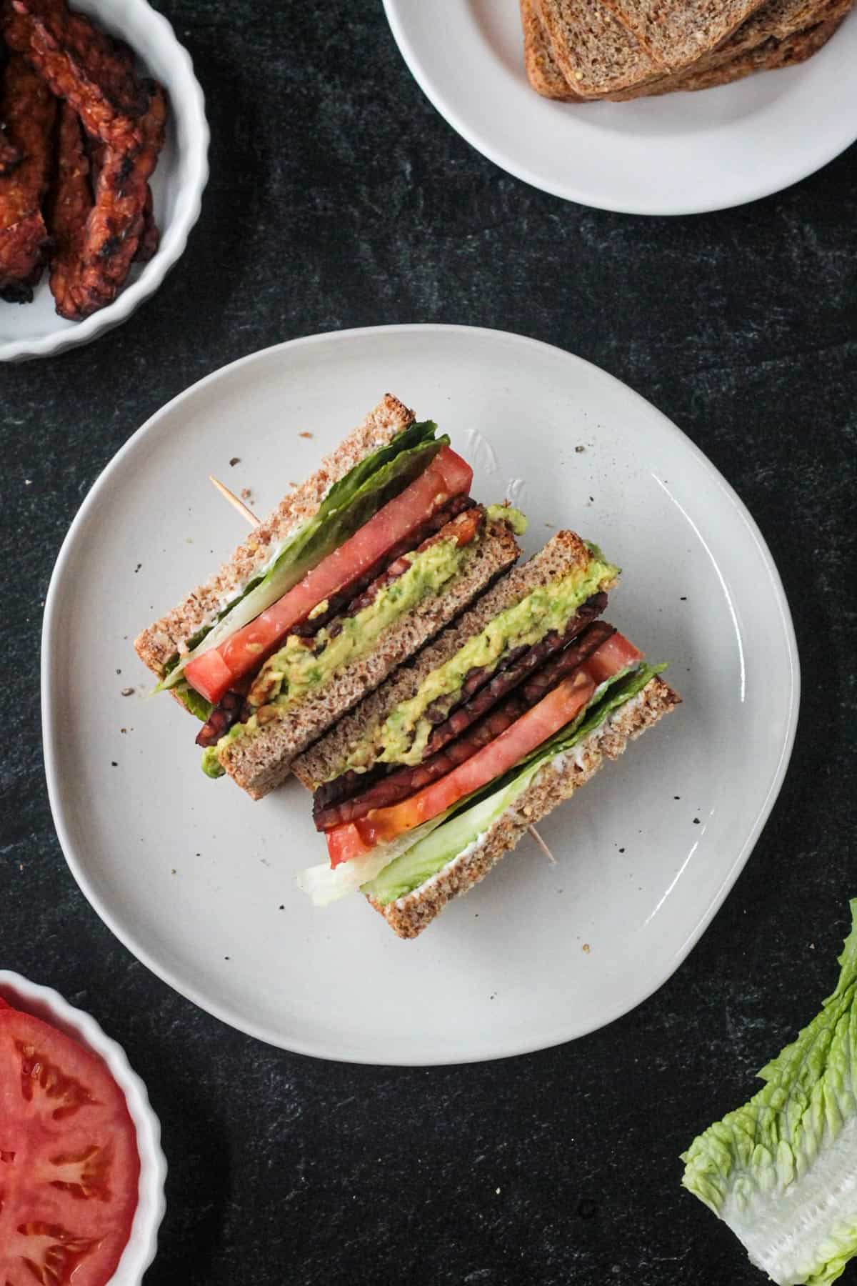 Two halves of a vegan blt sandwich on a plate.
