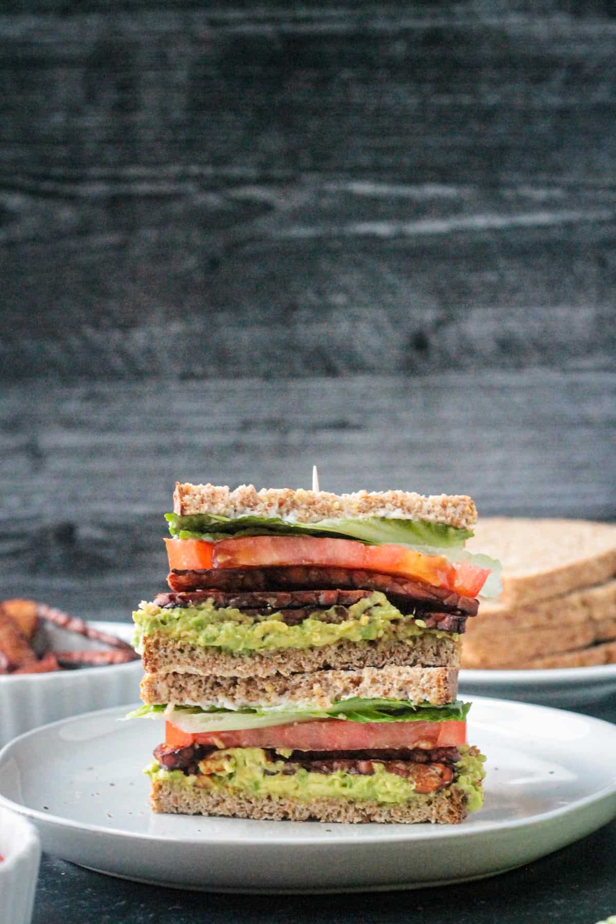 Two halves of a vegan blt sandwich stacked on top of each other.