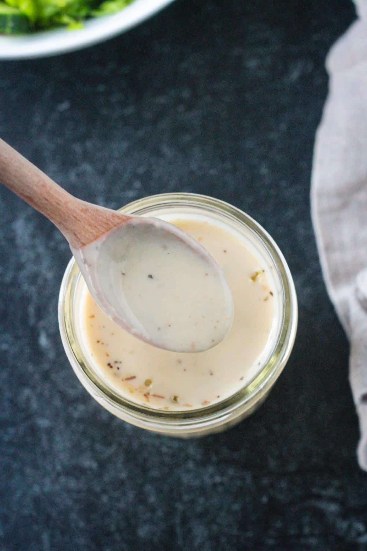 Spoonful of sauce being lifted from a jar.