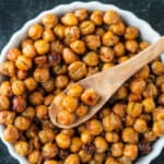 Seasoned roasted chickpeas in a bowl with a small wooden spoon.