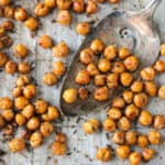 Spatula scooping up roasted chickpeas from a baking sheet.