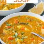 Chunks of potatoes, carrots, and celery in a bowl of red lentil soup.