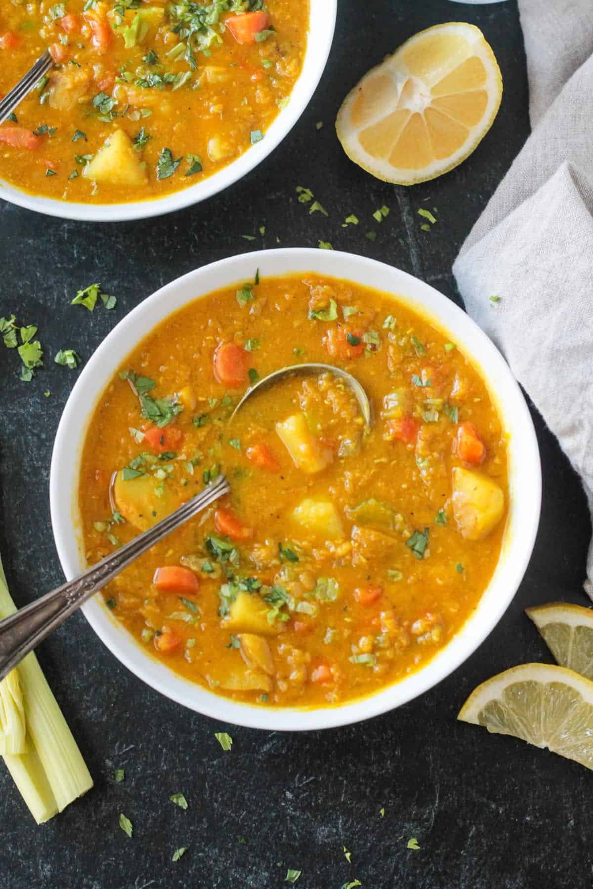 Metal spoon in a bowl of red lentil potato soup.