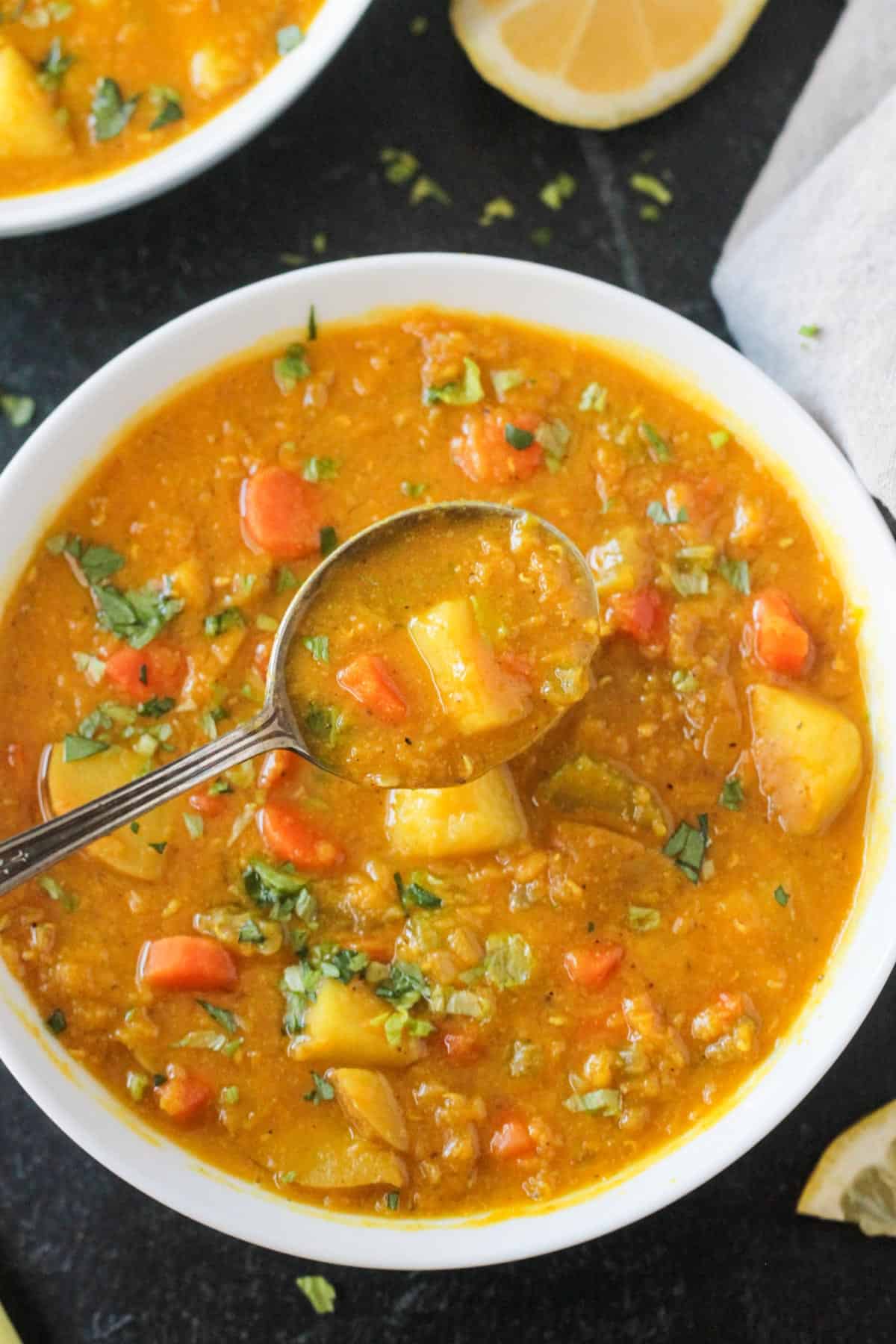 Close up of a spoonful of red lentil potato soup.