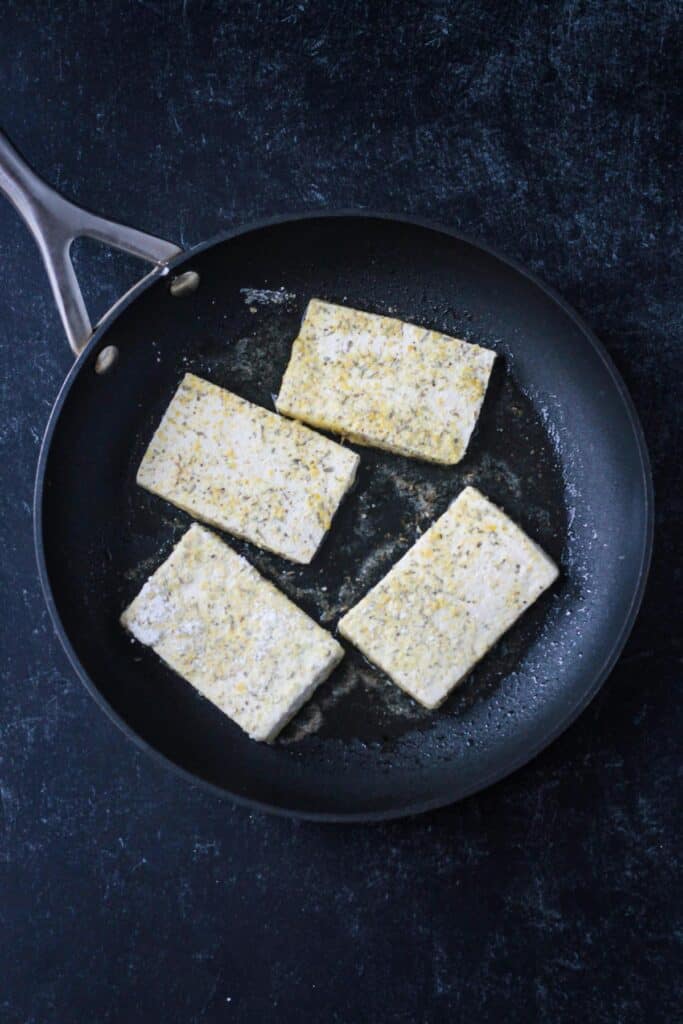 Four slices of tofu in a skillet.
