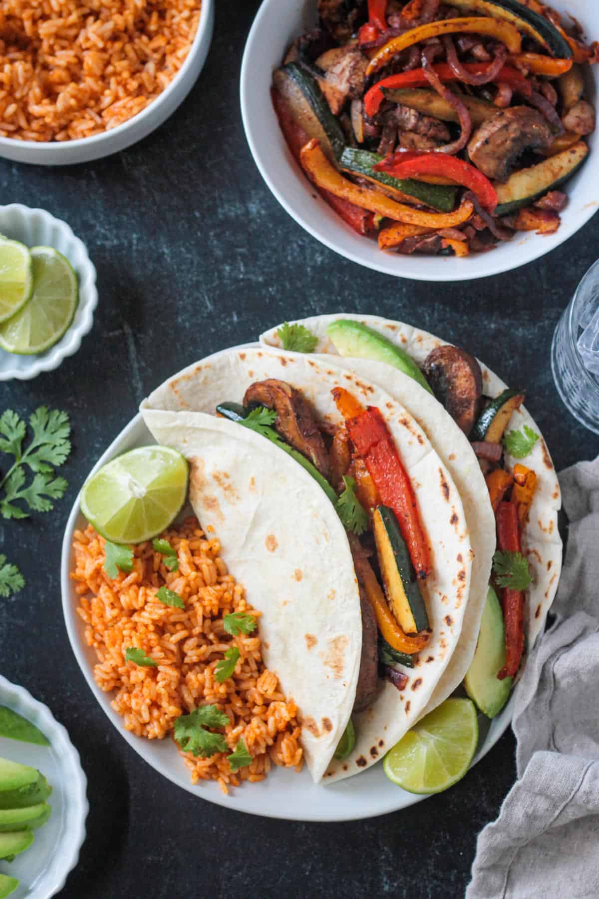 Two vegan fajitas on a plate with Spanish-style rice.