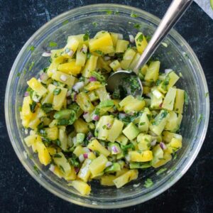 Diced pineapple, avocado, cilantro, and red onion mixed in a bowl.