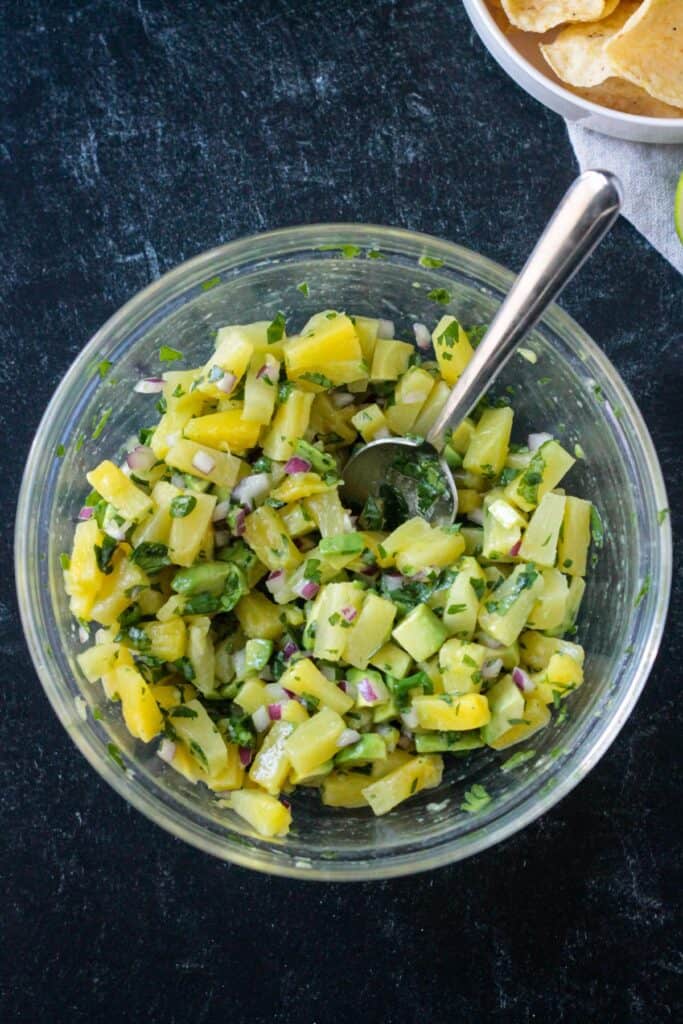 Diced pineapple, avocado, cilantro, and red onion mixed in a bowl.