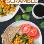 Overhead view of chickpea and spinach scramble on a plate with tomatoes and toast.