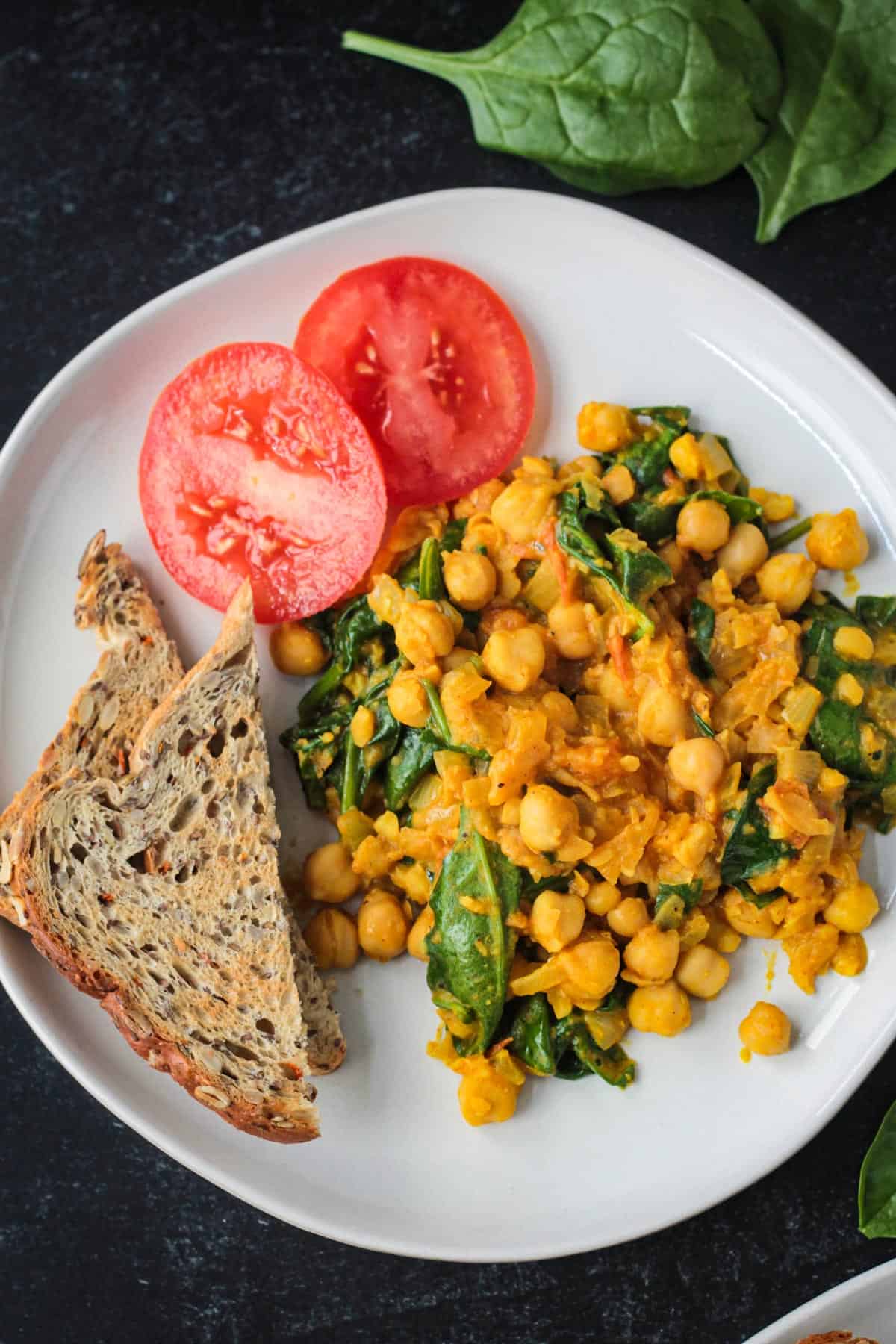 Vegan chickpea scramble on a plate with toast and tomato slices.