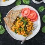 Two plates of chickpea scramble next to a cup of coffee and plate of toast.