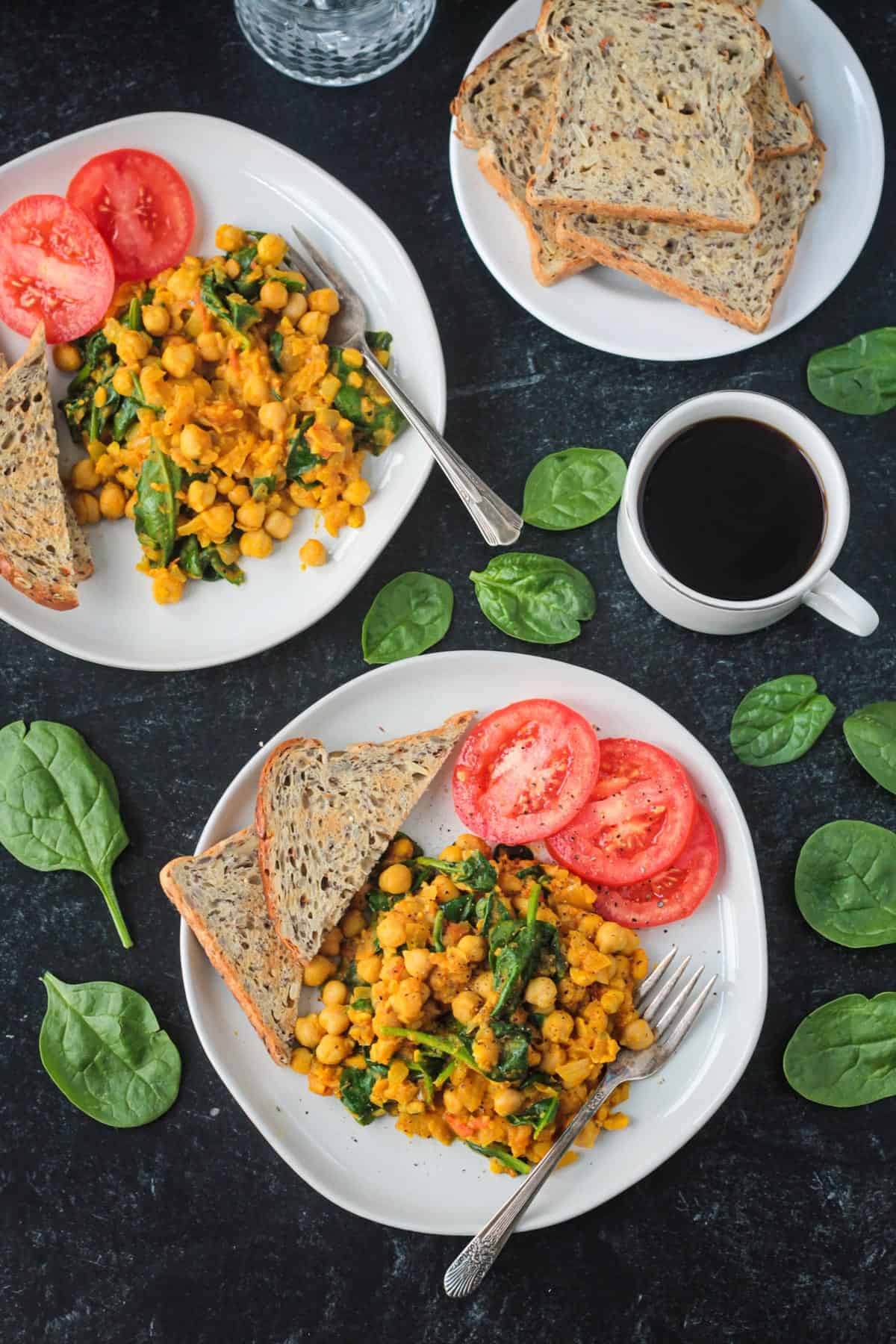 Two plates of chickpea scramble next to a cup of coffee and plate of toast.