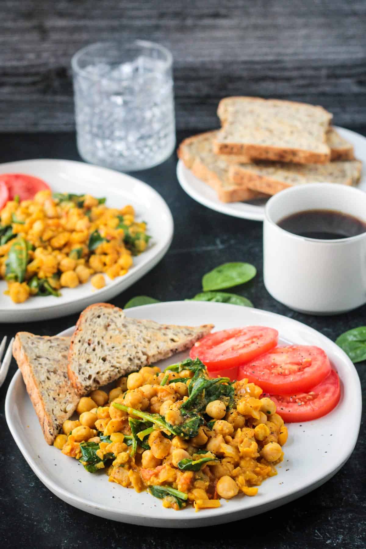 Serving of sautéed chickpeas and spinach next to a cup of coffee.