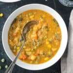 Metal spoon in a bowl of creamy vegetable soup.