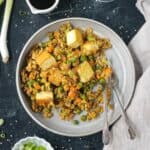 Curry fried rice with peas and carrots on a plate with two forks.