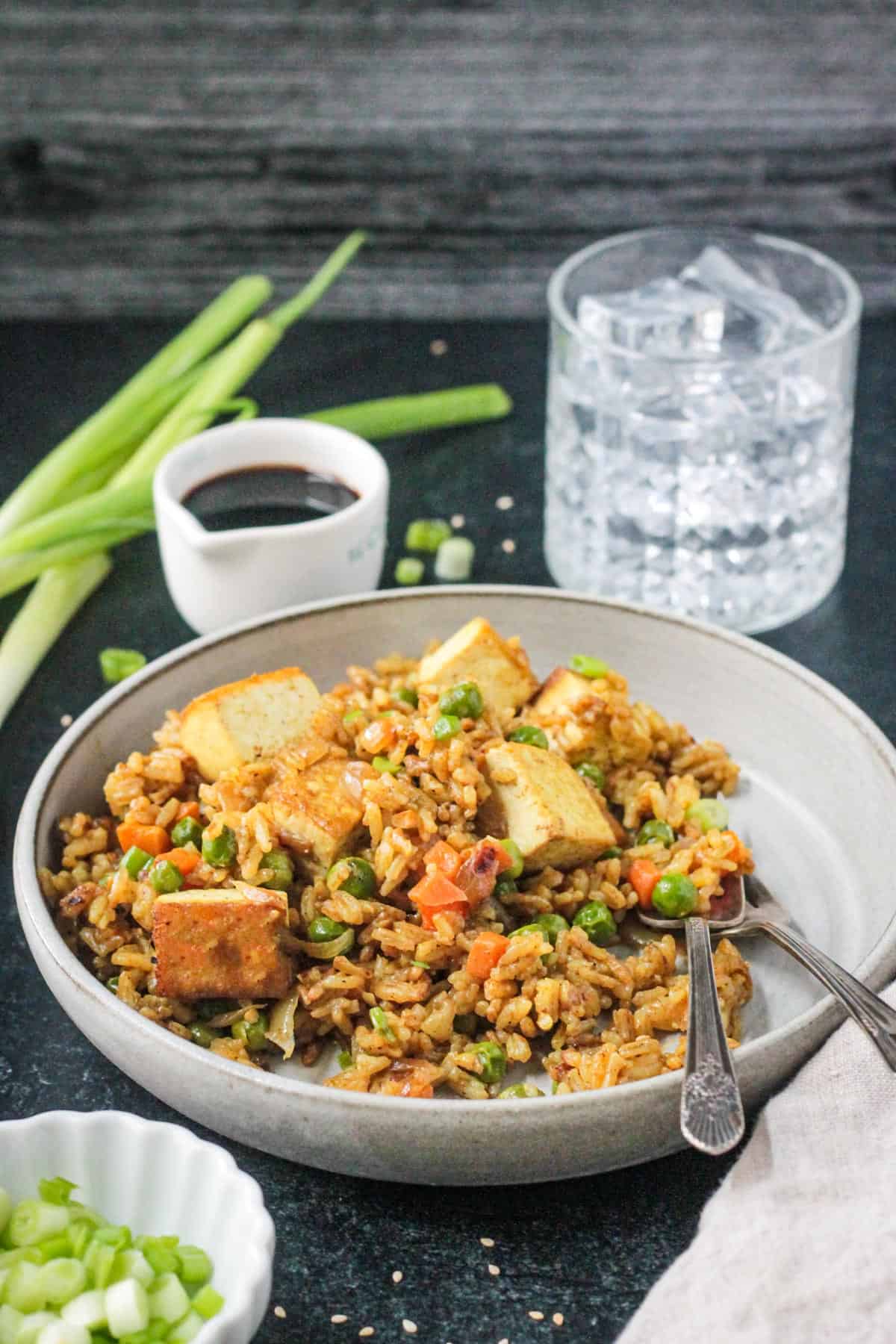 Two forks on a plate of a curry tofu fried rice.