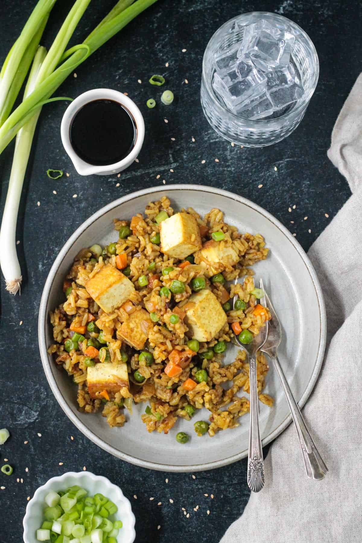 Curry fried rice with peas and carrots on a plate with two forks.