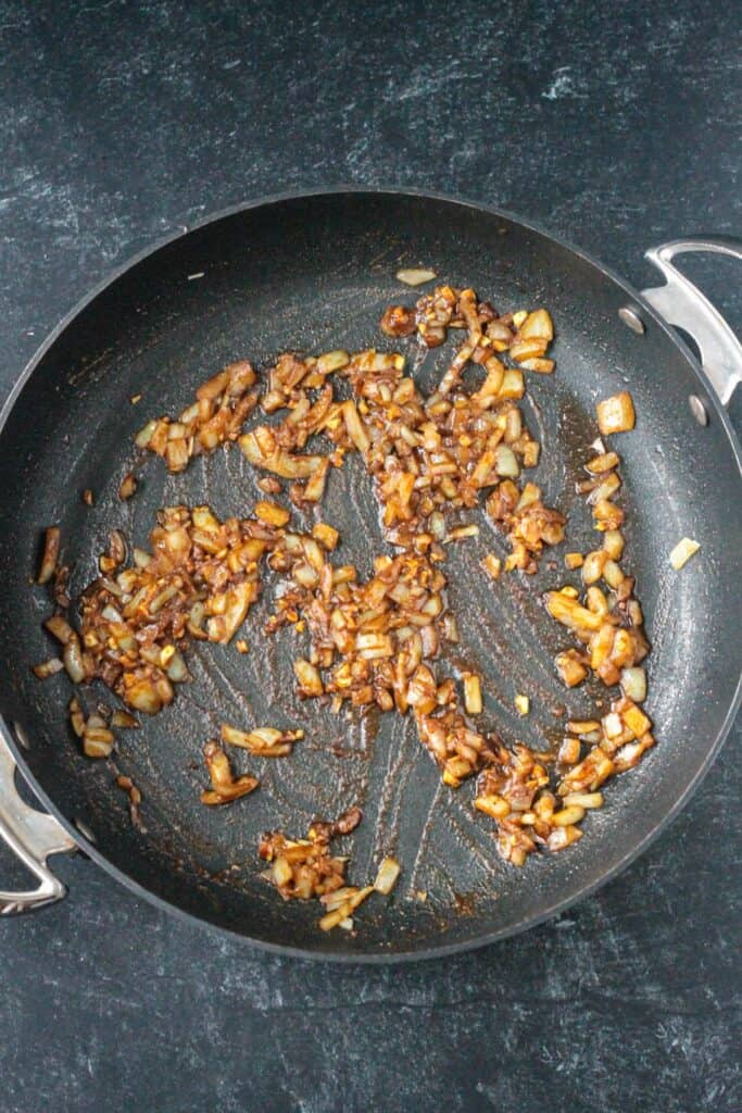 Onions and spices sautéing in a skillet.