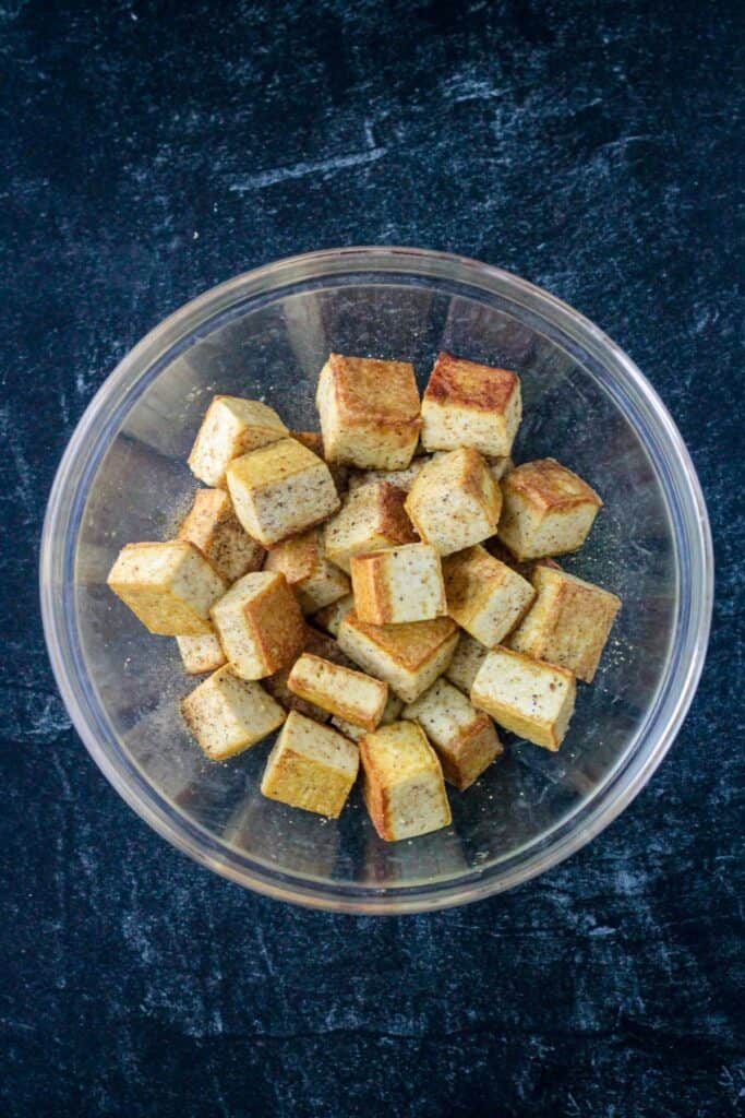 Seasoned fried cubes of tofu in a glass bowl.