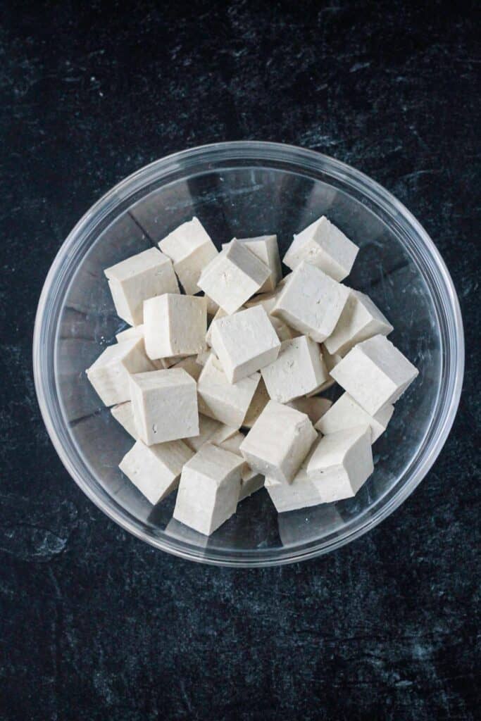 Raw tofu cubes in a glass bowl.