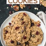 Pile of oatmeal cranberry walnut cookies on a plate.