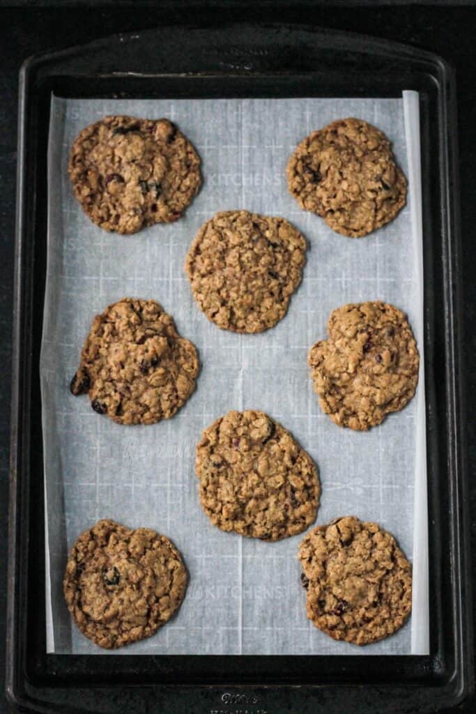 Eight baked cookies on a parchment paper lined cookie sheet.