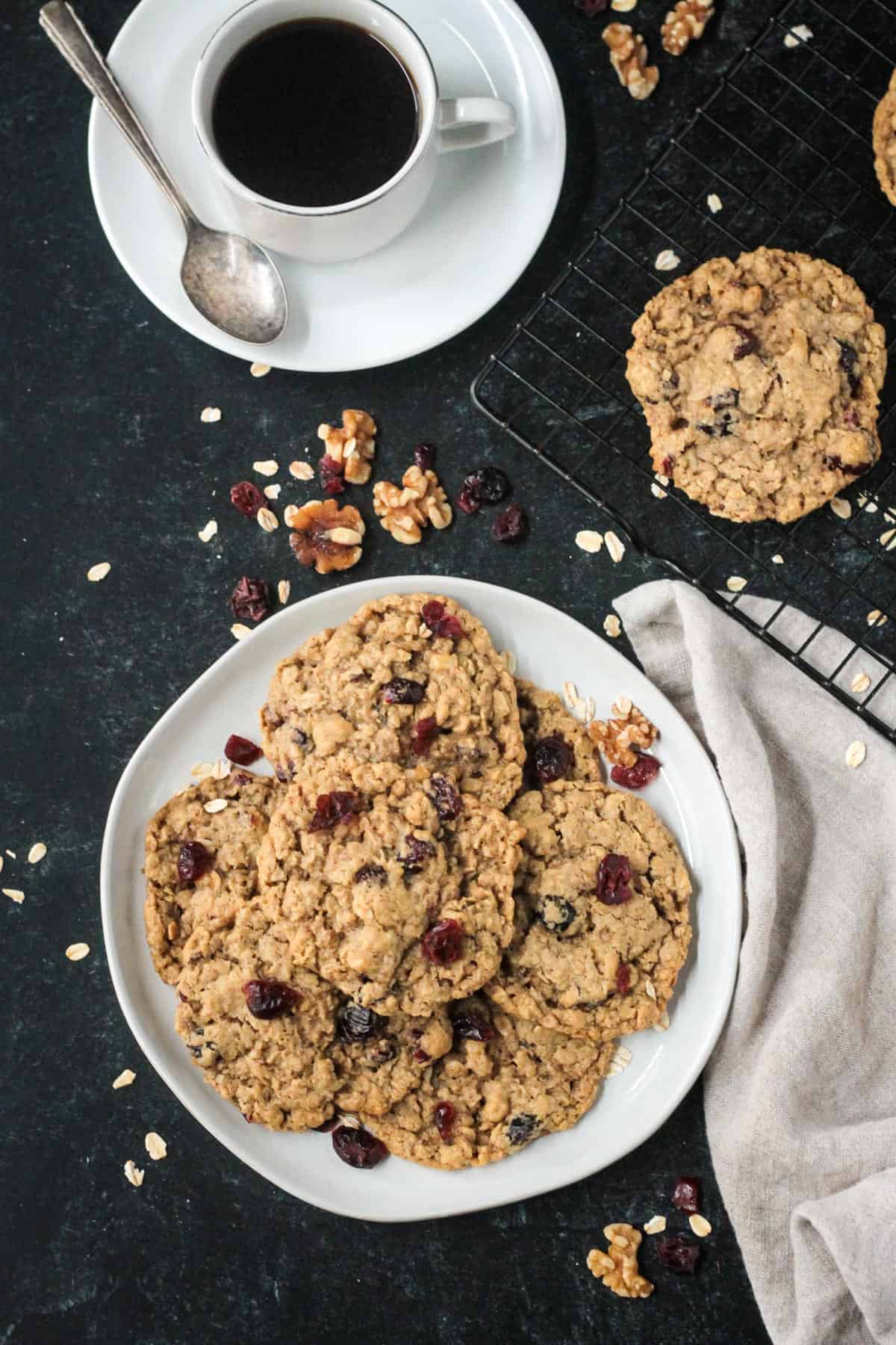 Plate of oatmeal cranberry cookies on a table with a cup of coffee.