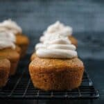 Close up of one frosted vegan pumpkin cupcake on a cooling rack.