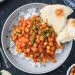 Chickpea tikka masala plated over rice with a side of naan.