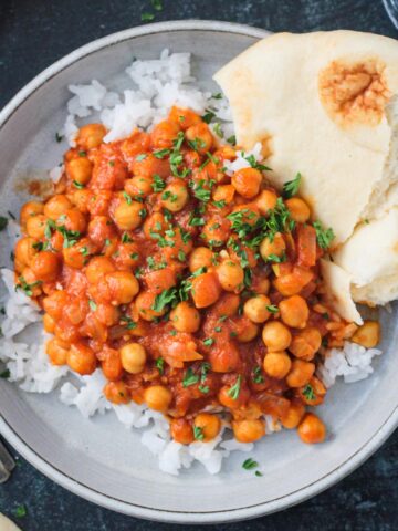 Chickpea tikka masala plated over rice with a side of naan.